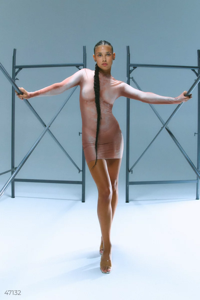 Жінка стоїть в бежевій сукні колекції TILO від бренду Gepur